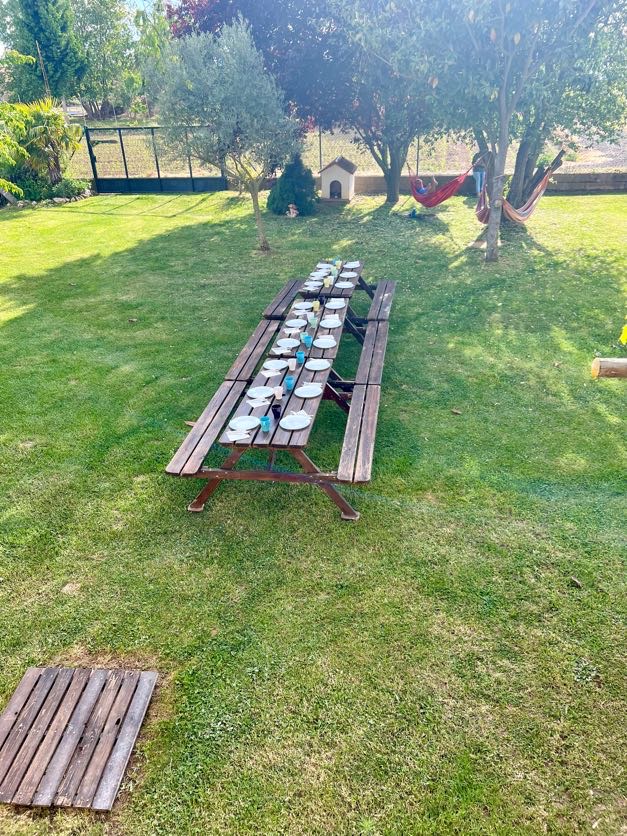A long table is set on green grass outside at one of the best albergues on Camino Frances