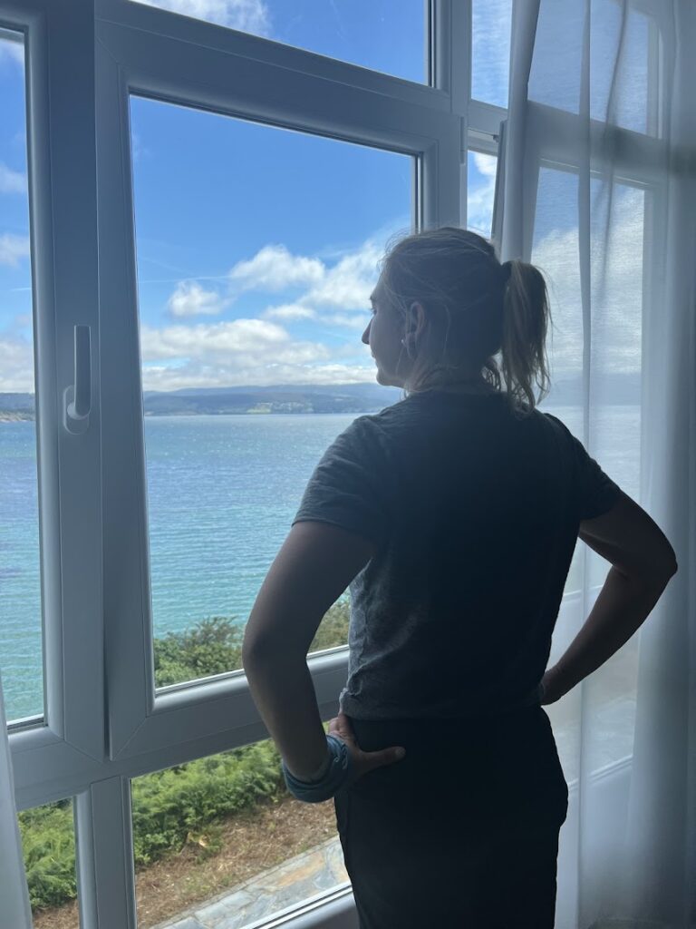 A woman looks out the window reflecting the best places to stay on the camino de santiago (frances)