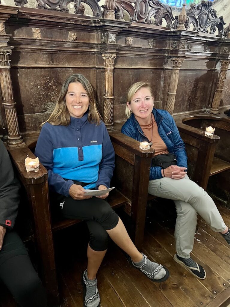 Two pilgrims sit in a church choir at an Albergue in Granon, among the best places to stay on camino de santiago