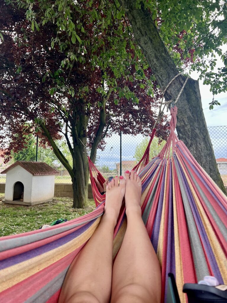 A pilgrim rests in a colorful hammock at a place to stay on camino de santiago