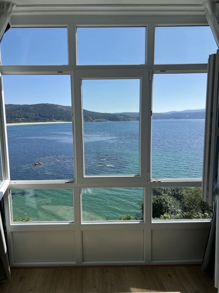 A large paned window overlooks a bluegreen sea at Hotel Mar de Fisterre one of the best places to stay at end of Camino de Santiago