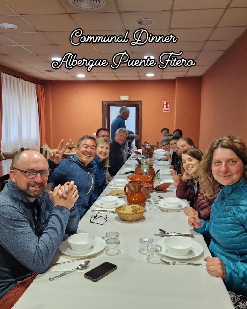 Group of pilgrims at a long dinner table at Puente Fitero, one of the best places to stay on Camino Frances