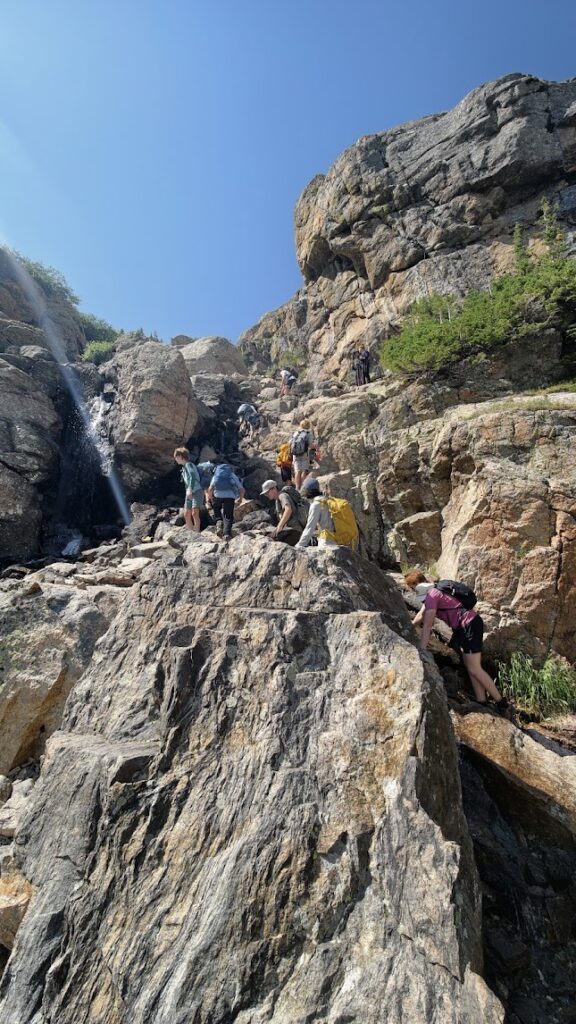 Photo of rocky vertical mountain and people climbing up it